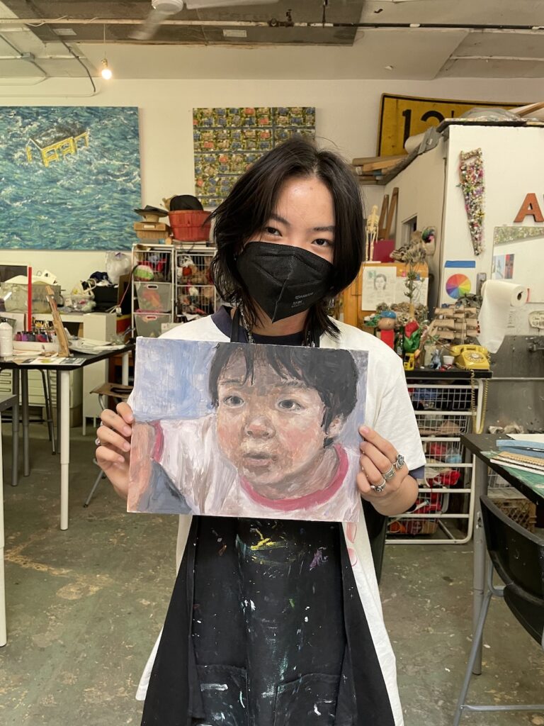 A girl holding a painting of a boy