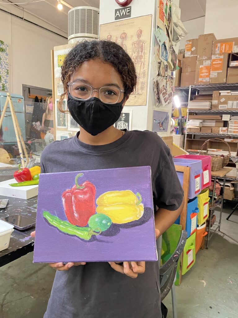 A girl holding a painting of fruits