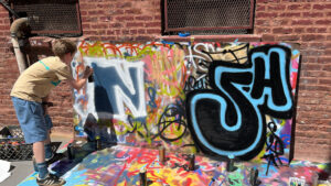 A person is painting graffiti on the side of a building.