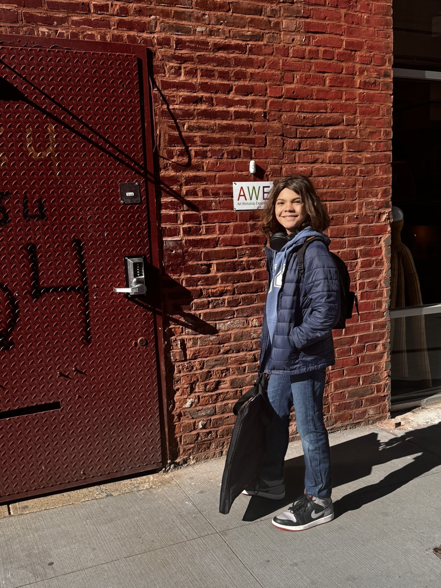 A woman standing in front of a building with a skateboard.