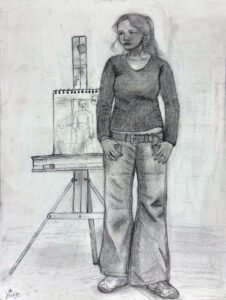 A woman standing in front of an easel.
