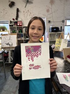 A girl holding up a piece of paper with a design on it.