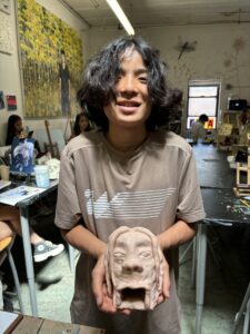 A person holding a clay mask in their hands.