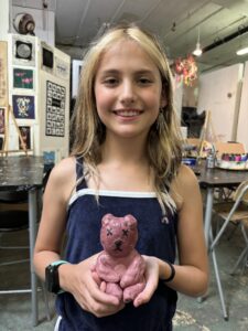 A girl holding a pink bear in her hands.