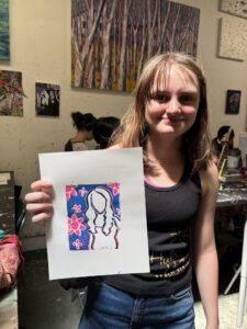 A girl holding up a picture of herself.