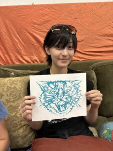 A woman holding up an animal drawing.