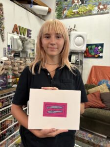 A woman holding up a box with pink design on it.