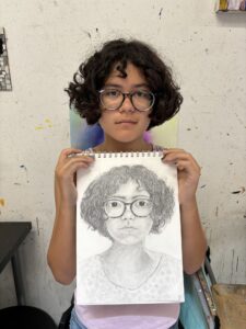 A woman holding up a drawing of herself.