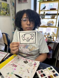 A woman holding up an elephant picture at a table.