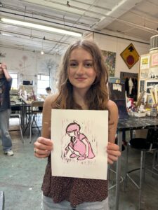 A girl holding up a picture of herself in pink.
