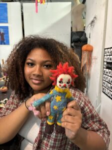 A woman holding a clown doll in her hand.