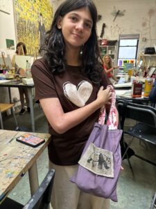 A woman holding onto a purple bag in front of her face.