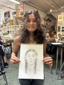 A woman holding up a drawing of herself.