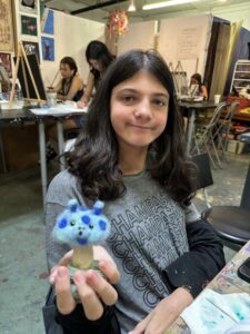 A girl holding a cupcake with blue frosting on it.