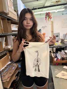 A woman holding up a bag with an image of a giraffe on it.