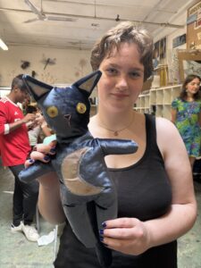 A woman holding a stuffed cat in her hand.