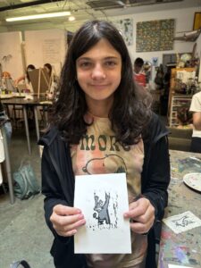 A girl holding up an animal drawing.