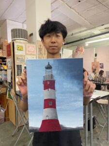 A man holding up a picture of a lighthouse.