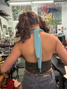 A woman with curly hair wearing a blue neck tie.