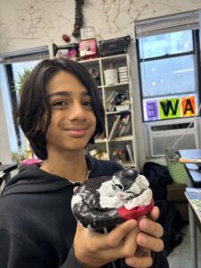 A boy holding a doughnut with black and white frosting.