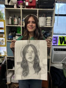 A woman holding up a drawing of herself.