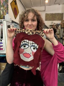 A woman holding up an altered art piece.