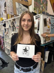 A girl holding up a card with an image of a star.