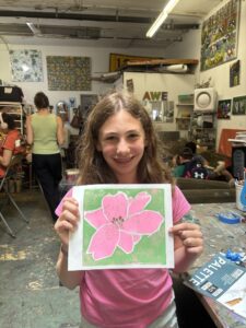 A girl holding up a pink flower picture.