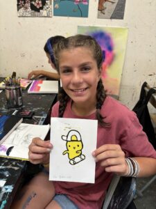 A girl holding up a picture of a yellow character.