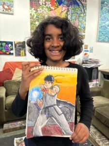 A girl holding up a drawing of a boy.