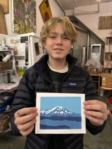 A boy holding up a picture of a mountain.