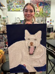 A girl holding up an animal painting.
