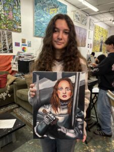 A girl holding up a painting of herself.