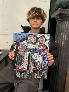 A person holding up a painting of a city.