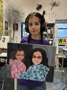 A girl with headphones holding up an image of two girls.