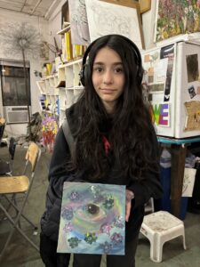 A girl holding up an art project in front of other people.