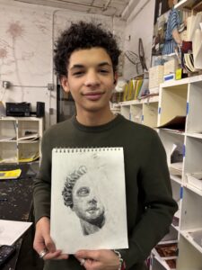 A young man holding up a drawing of himself.