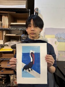 A boy holding up a picture of a pelican.