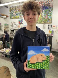 A boy holding up a painting of a bear.