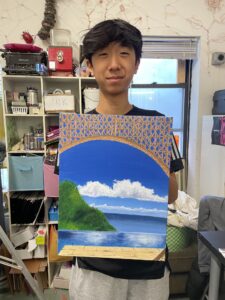 A man holding up an art work in front of a room.