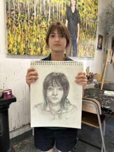 A woman holding up a drawing of herself.