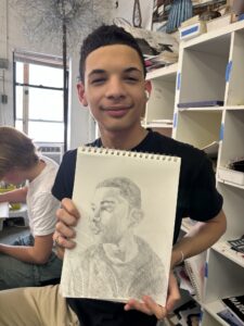 A man holding up a drawing of himself.