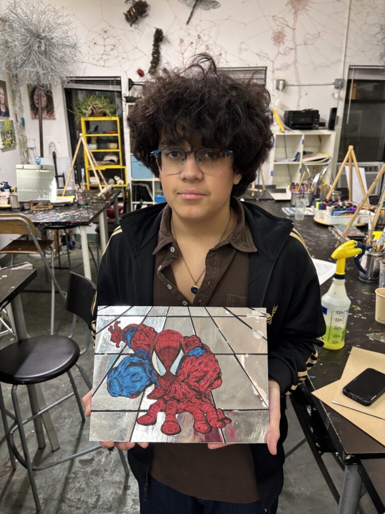 A man holding up a painting of spider-man.