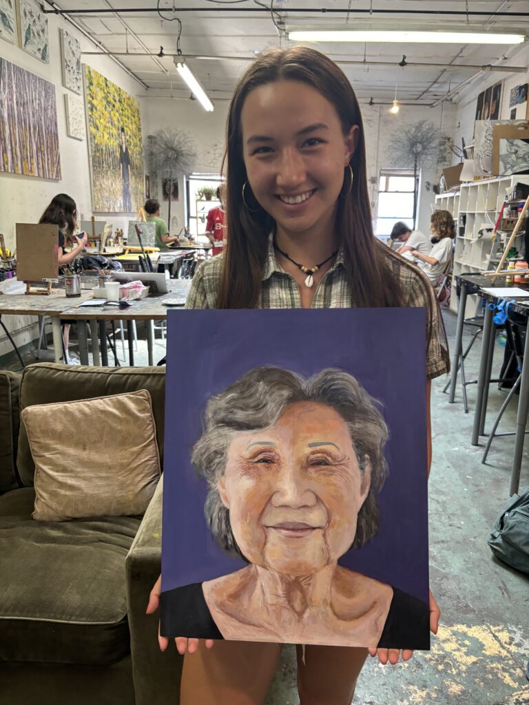 A girl holding up an old woman 's portrait.