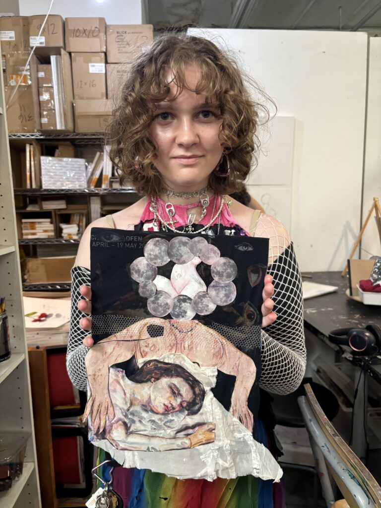 A woman holding up an altered art piece.