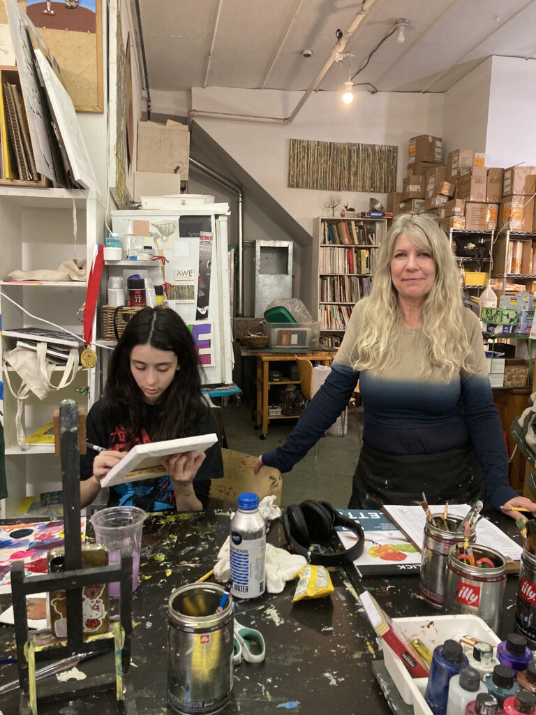 Two women sitting at a table with many items.