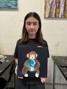 Girl holding painting of monkey with Earth.