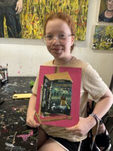 Girl holding painted book cover.
