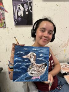 Girl holding painted duck canvas.