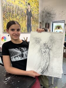 Girl proudly displays her angel drawing.